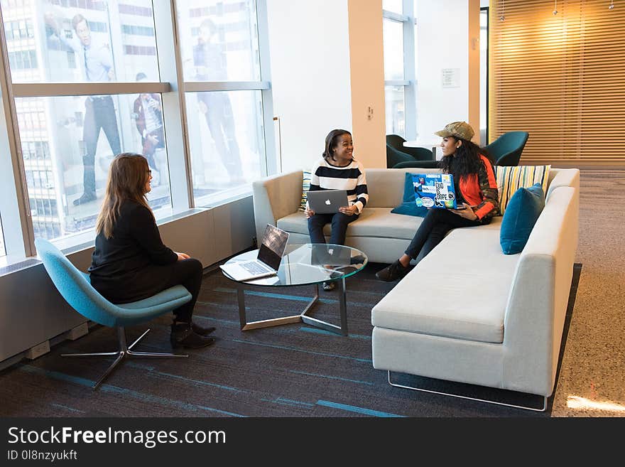 Women Sitting on Sofa Holding Laptops