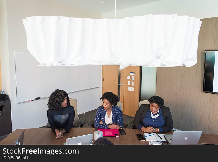 Three Women Wearing Formal Clothes Sitting in Front of Conference Table