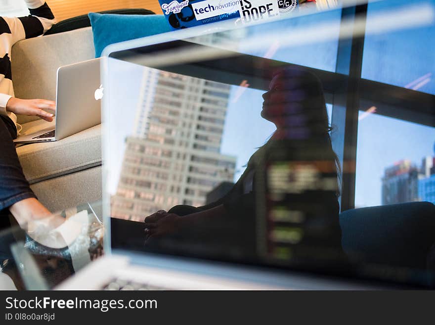 Photo of Gray Laptop Reflecting a Sitting Woman