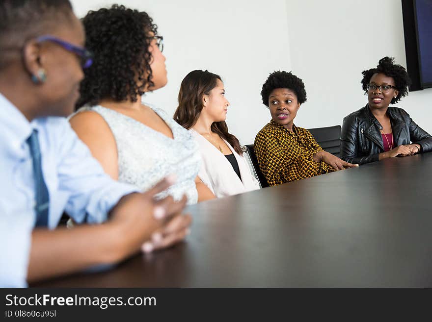 Four Women and One Man Sitting Near Table Inside Room