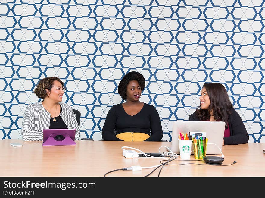 Three Women Sitting in Front of a Wooden Table