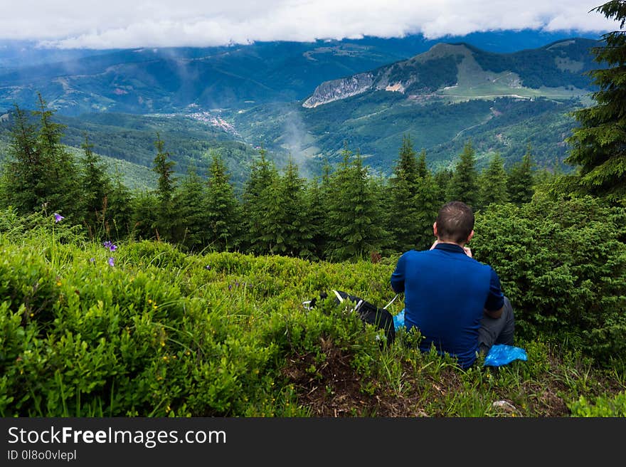 Man Wearing Blue Shirt Sitting On Green Grass