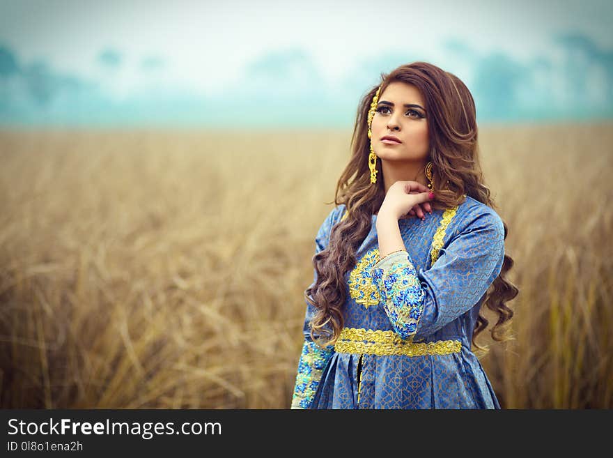 Brunette Haired Woman in Blue Dress Stranding in an Open Field