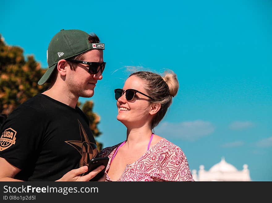 Selective Focus Photo of Couple Stands Behind Green Tree at Daytime