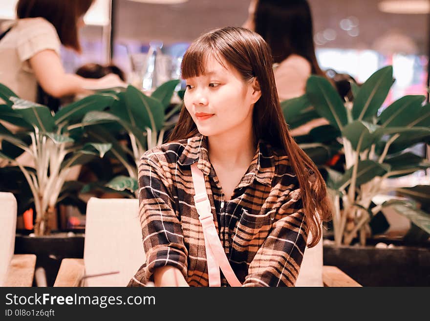 Woman Wearing Black and Brown Plaid Sport Shirt Sitting on Sofa