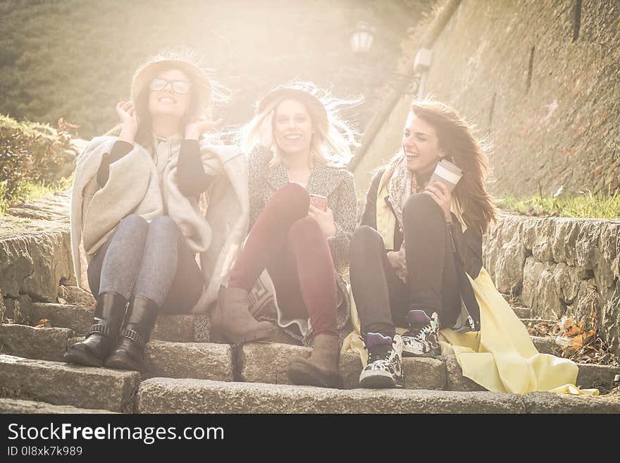 Three young girls sitting on the stairs at the public park.