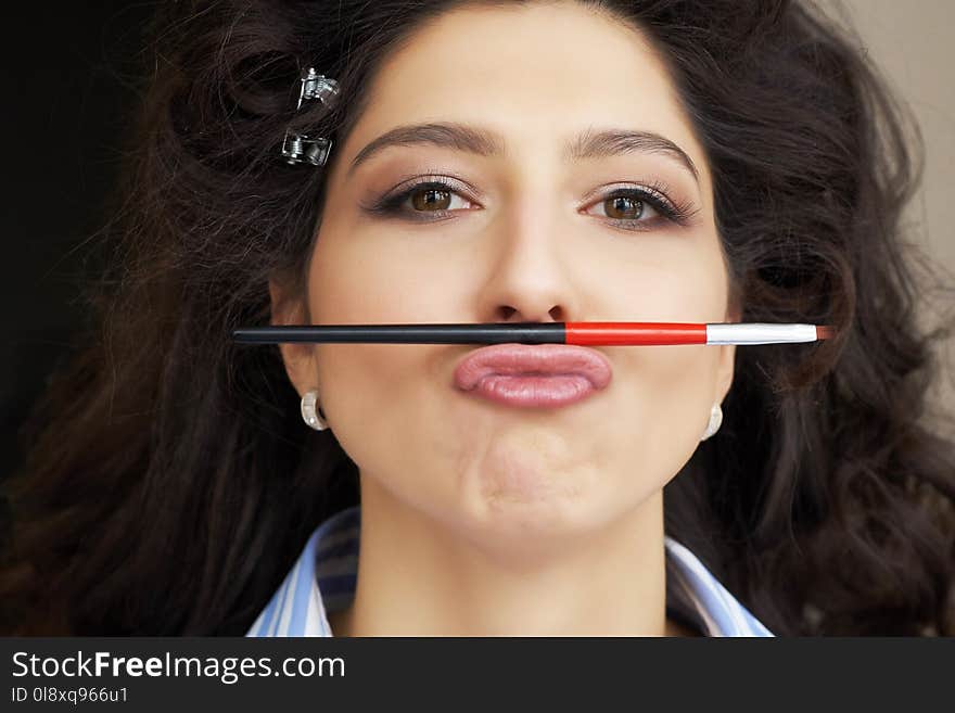 Young model holds a makeup brush in the form of a mustache in hairstyle and makeup salon. little fun during the long