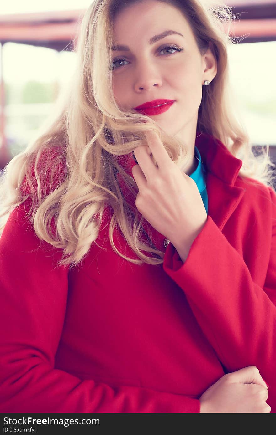 Outdoor fashion portrait of glamour young cheerful stylish lady wearing trendy red coat. Blonde long hair. Style photo