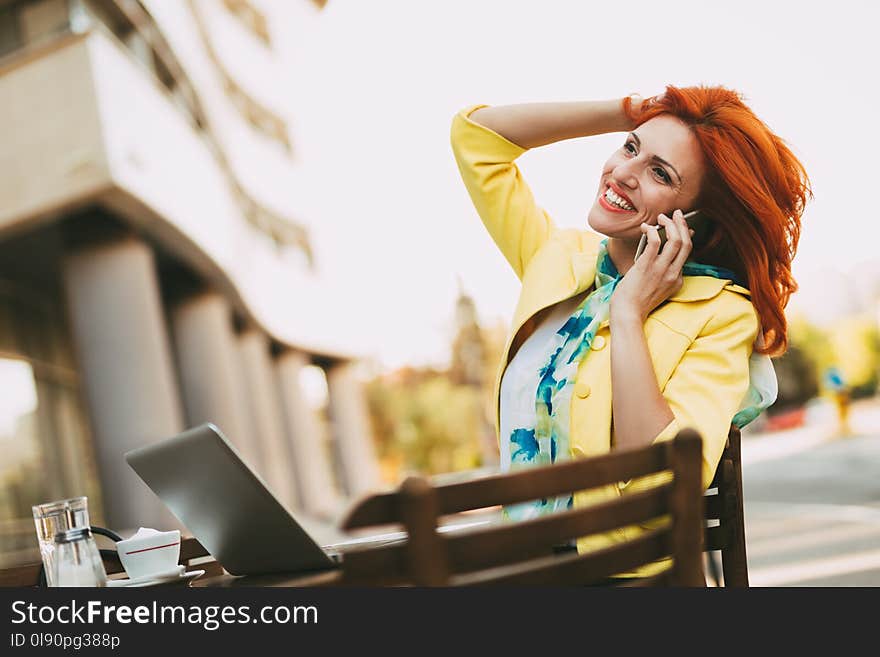 Successful businesswoman using phone on a coffee break in a street cafe. Successful businesswoman using phone on a coffee break in a street cafe.