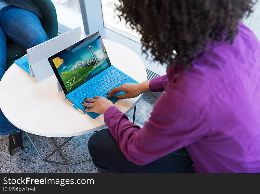 Person Using Blue Laptop Sitting Beside Table