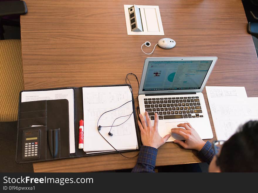 Person in Blue Dress Shirt Facing White Laptop on Brown Wooden Table