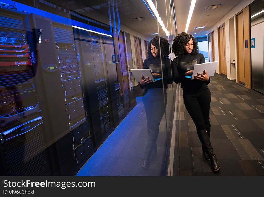 Woman Holding Laptop Beside Glass Wall