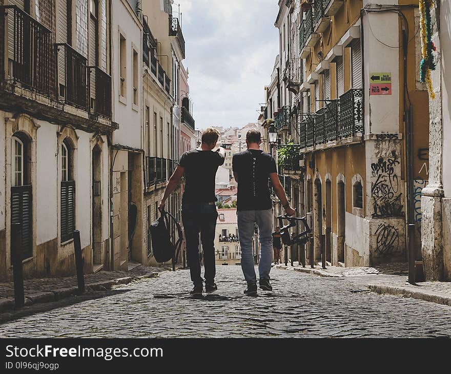 Two Man Walking in Between of Buildings Toward With Concrete Building