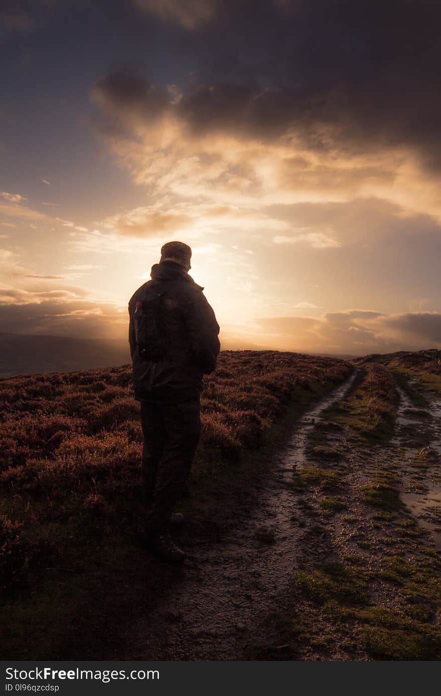 Man Standing in Muddy Field Path.