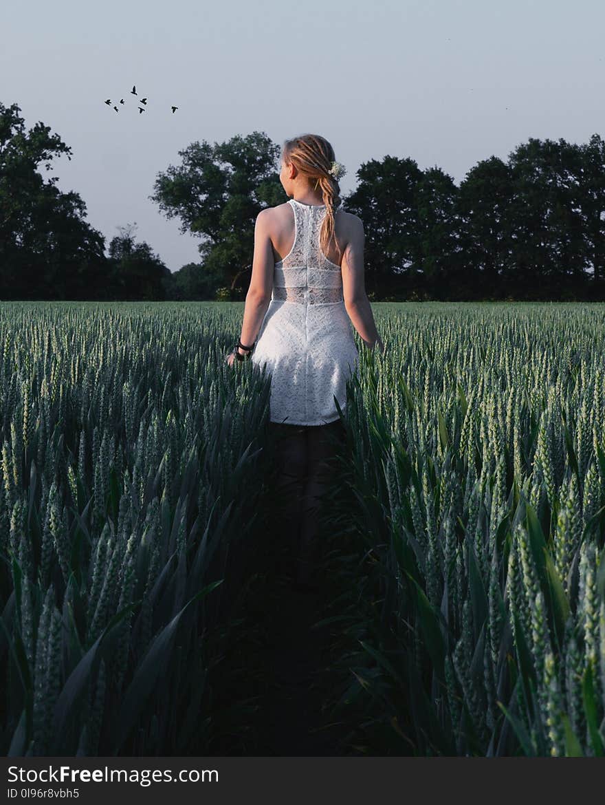 Woman in White Sleeveless Dress Near Green Plants