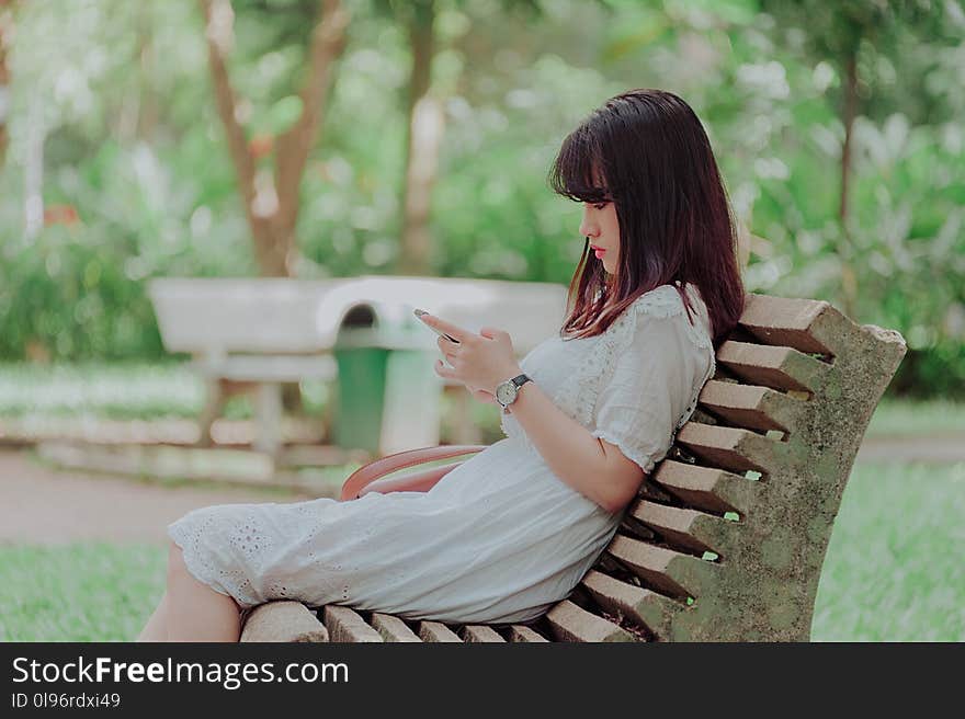 Woman Wearing White Dress Sitting on Bench