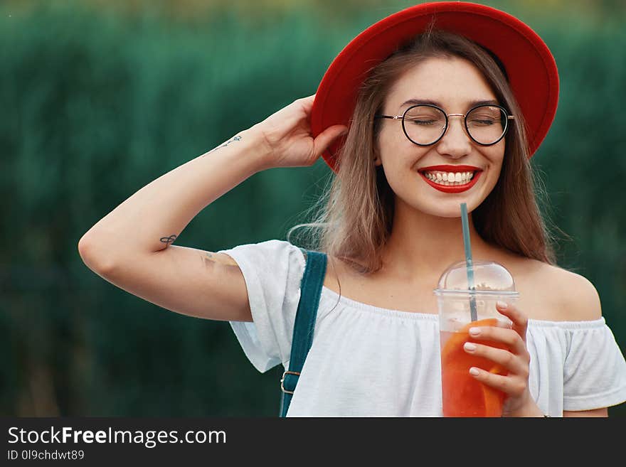 A Young stylish woman having a refreshing drink while walking