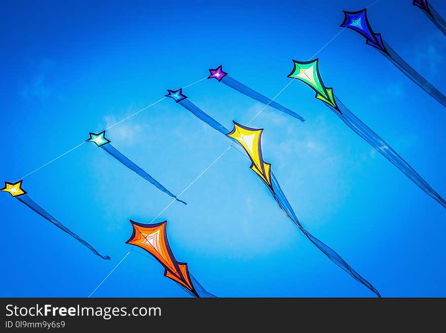 Close up image of brightly colored flying kites against a summer blue sky