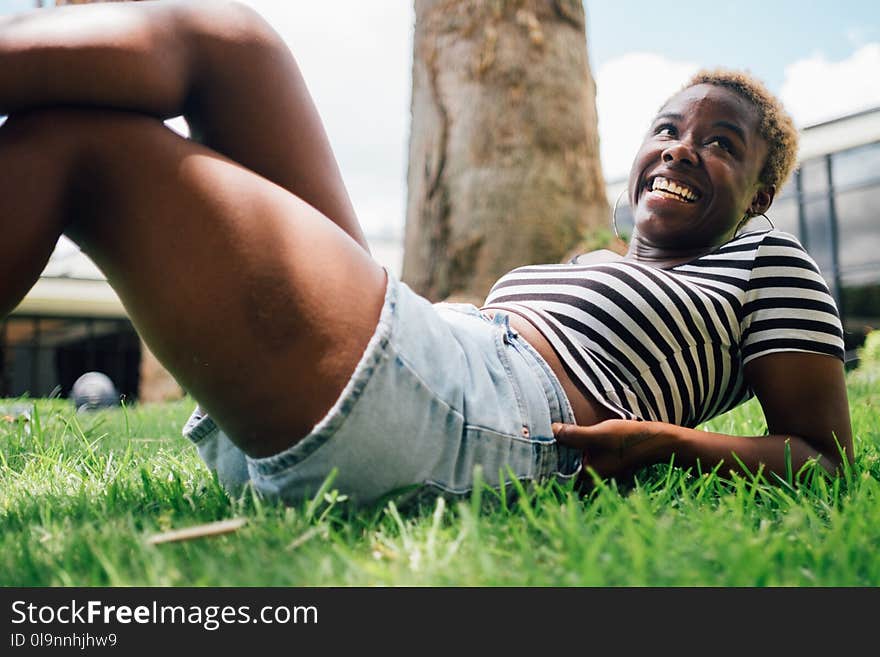 Woman Wearing Black and White Striped Shirt Lying on Green Grass at Daytime