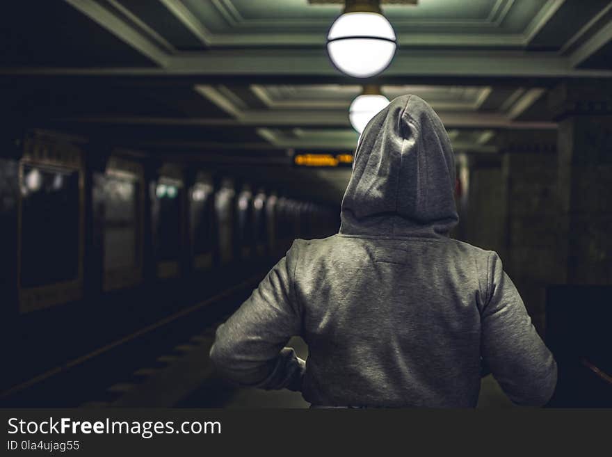 Person Wearing Gray Hooded Jacket in Train Station