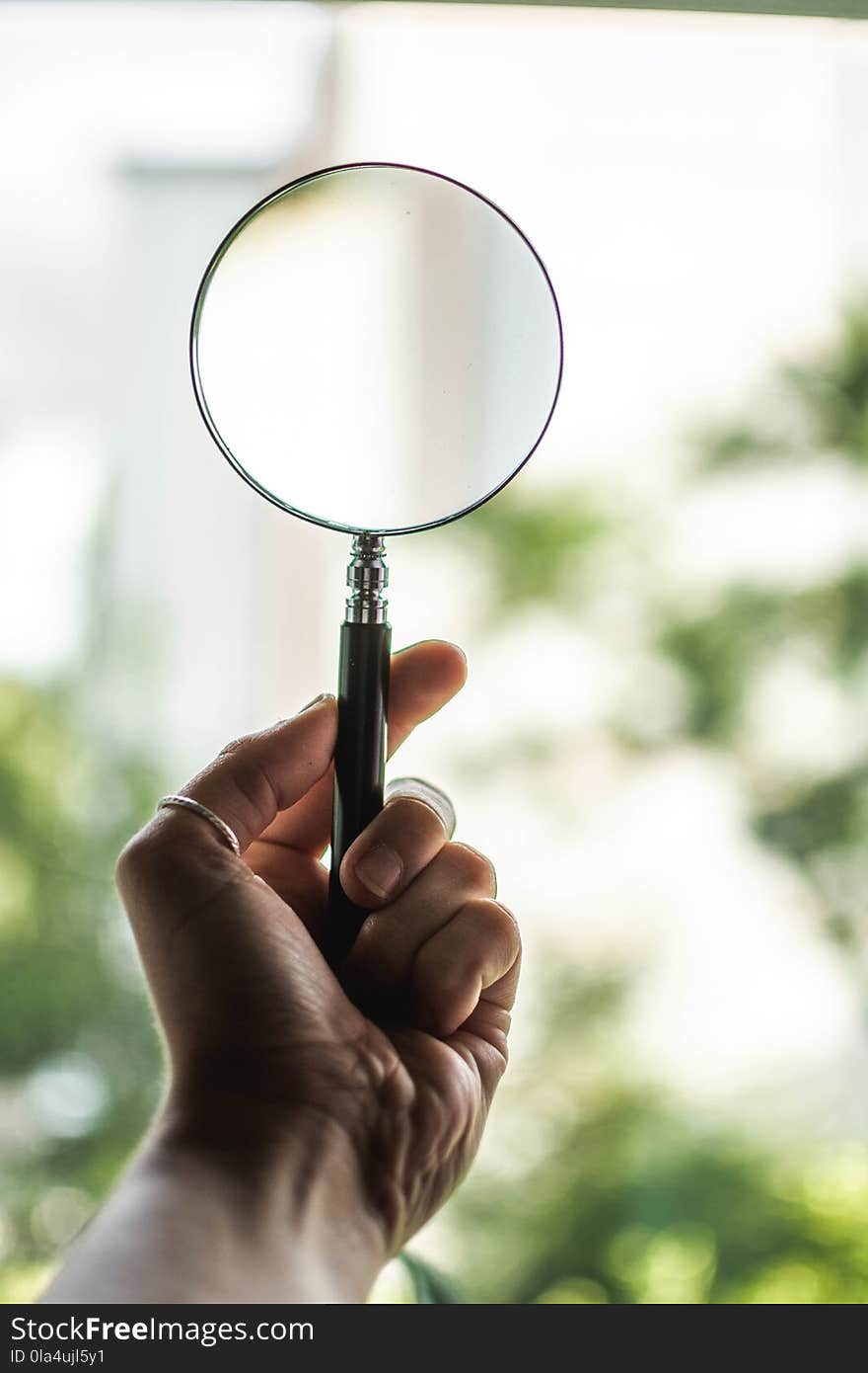 Tilt Shift Lens Photography of Person Holding Magnifying Glass