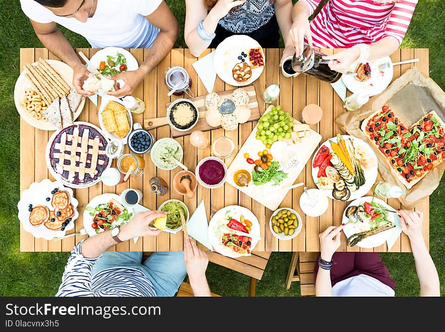 Top view on garden table with salad, fruits and pizza during out