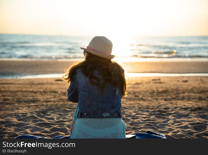 A girl sitting on the beach at the sunrise, admiring and enjoying the sea breeze