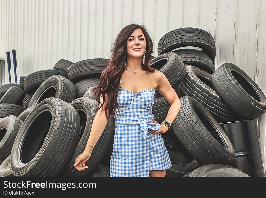 Woman Wearing Blue Flannel Dress Standing in Front Car Tires