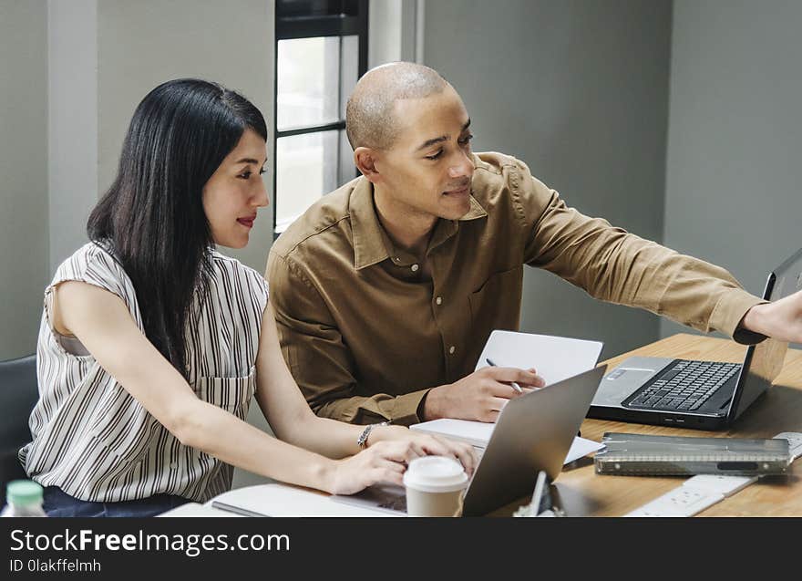 Man and Woman Looking at Laptop Computers