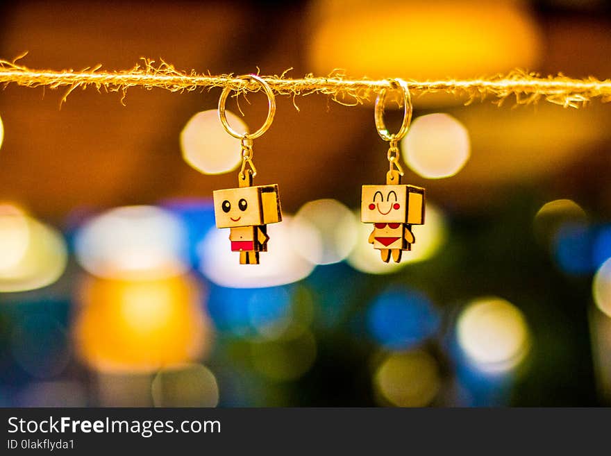 Two Brown Wooden Character Keychains Hanged on Brown Rope