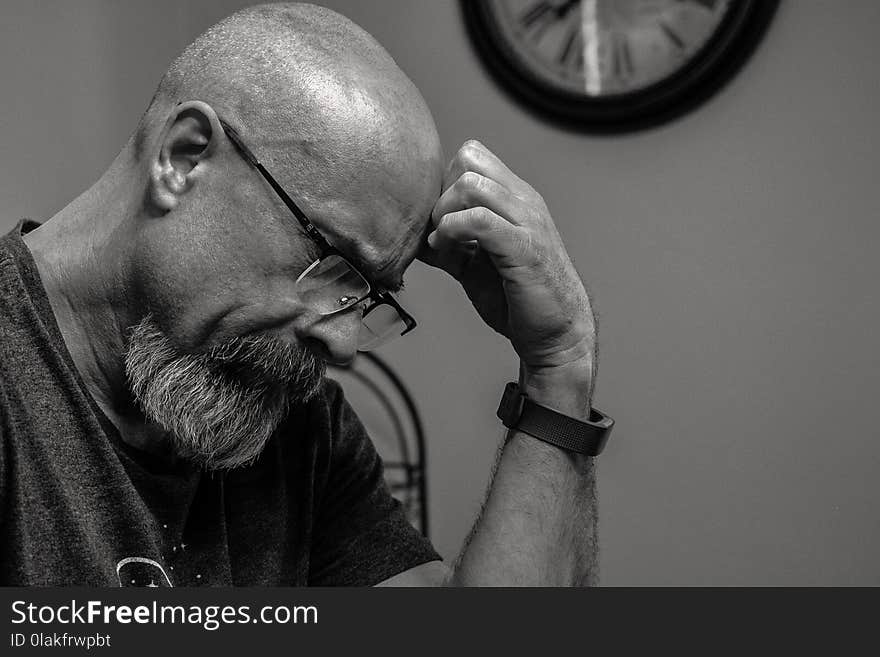 Grayscale Photo of Man Thinking in Front of Analog Wall Clock