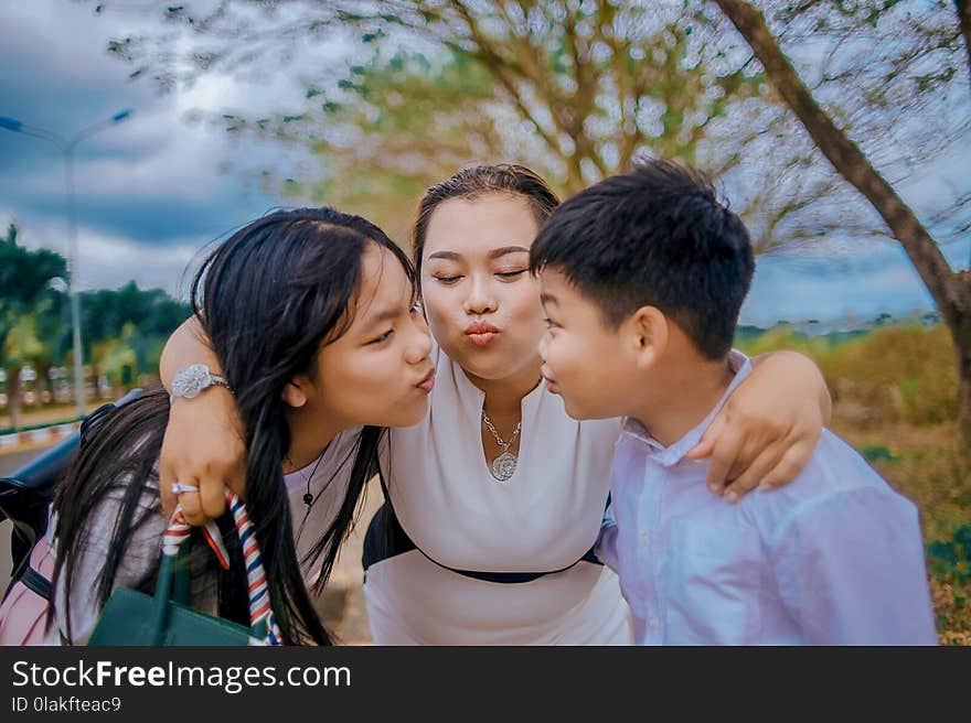 Three Person Kissing Near Tree