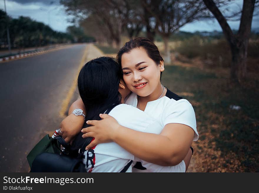 Two Women Hugging Each Other Standing on Pathway of the Road