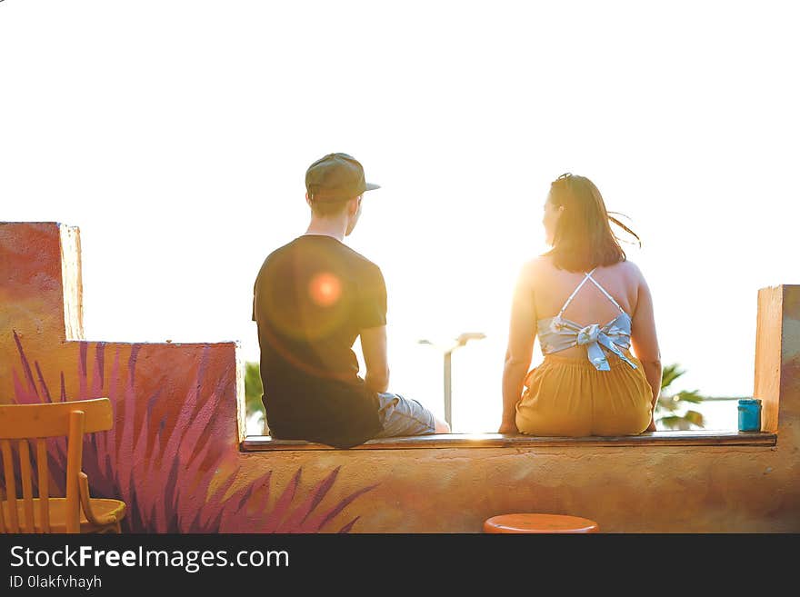 Man and Woman Sitting on Ledge