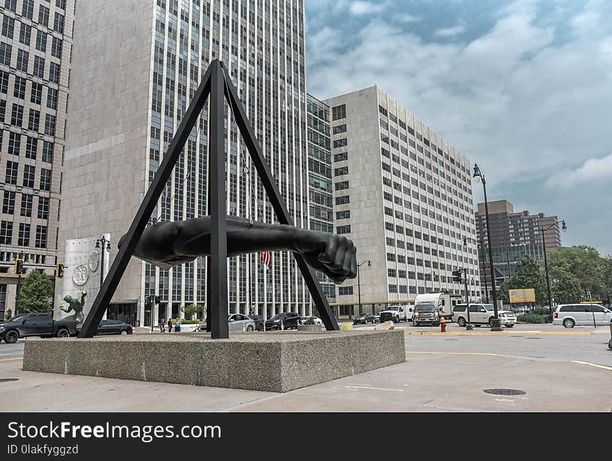 Statue of Human Arm Near Gray Buildings