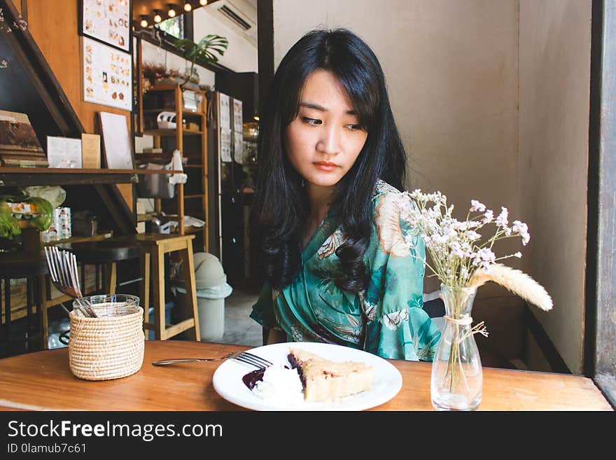 Beautiful Asian woman sitting in the cafe with a plate of dessert. Lifestyle concept.