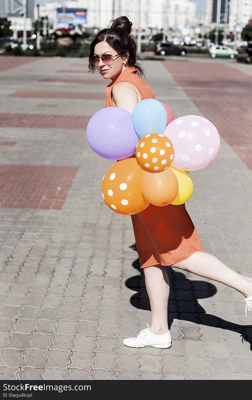 Happy young woman with balloons on the city square on a summer day