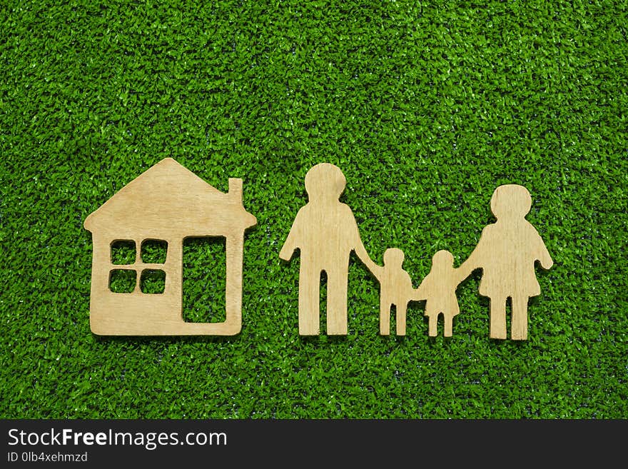 Family symbols and houses made of natural wood on the background of green grass symbolize the eco-house. Conceptual ideas, purchase of sales, credit, mortgage