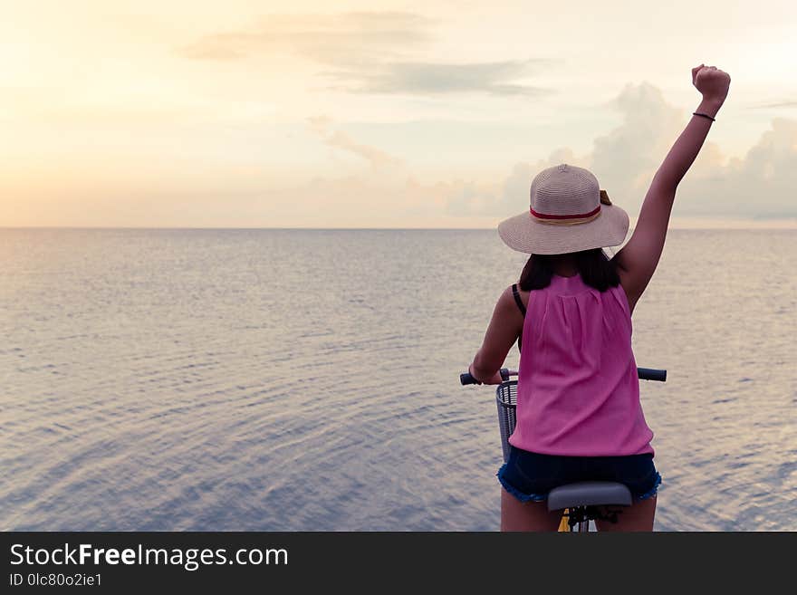 Asia teenager girl sit on the bike with both hand cheerful background sunset at the sea with copy space. Asia teenager girl sit on the bike with both hand cheerful background sunset at the sea with copy space.