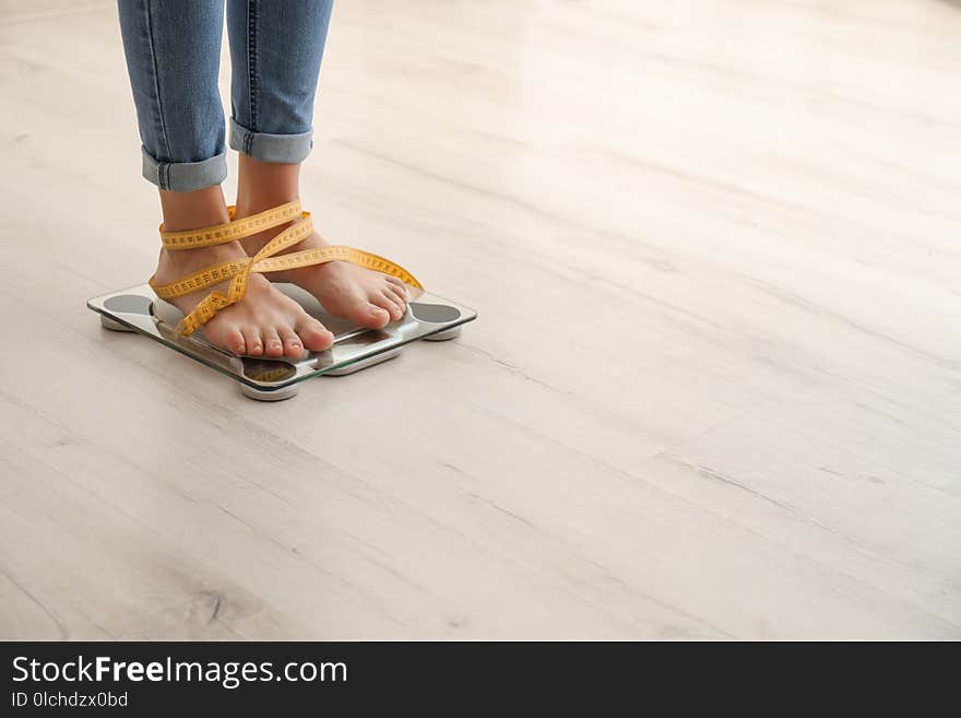 Woman with tape measuring her weight using scales