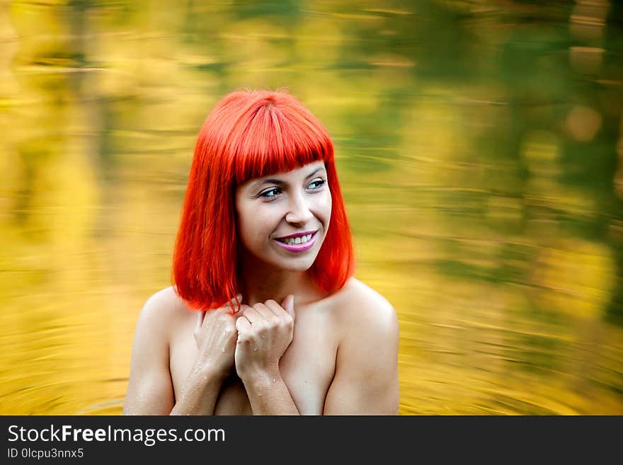 Happy girl with red hair on a lake without clothes