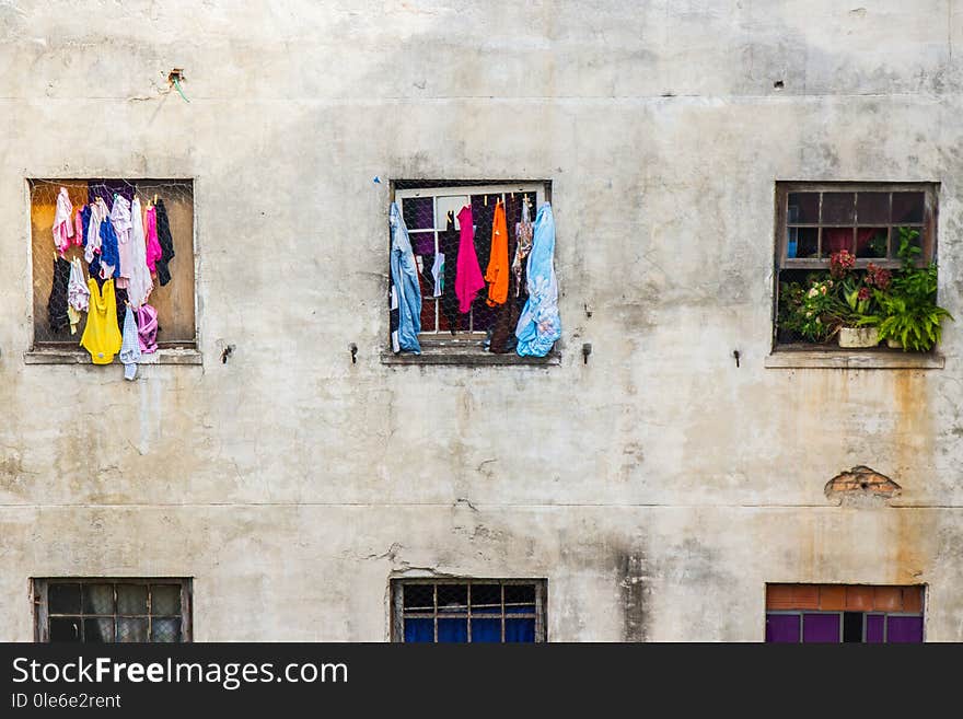 Square windows of homes with clothes and flowers in a decayed building with cracked walls. No people. Square windows of homes with clothes and flowers in a decayed building with cracked walls. No people.