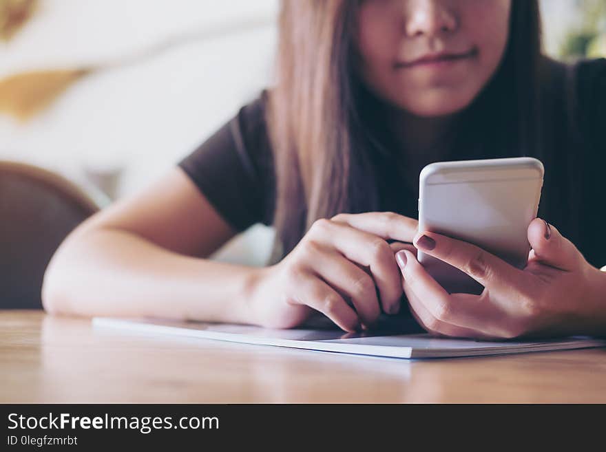 A beautiful Asian girl with smiley face using smart phone in modern cafe