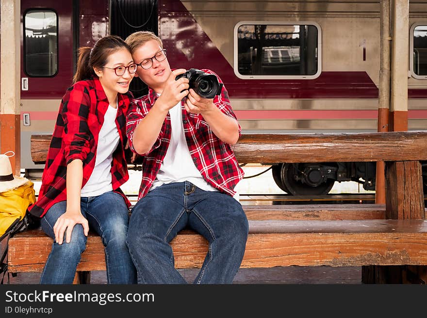 Happy young couple travellers together on vacation taking a photo at the train station, travel concept, couple concept