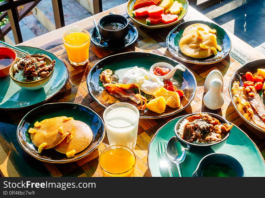 Healthy breakfast set with egg bacon pancakes orange juice milk bread coffee and other on wooden table