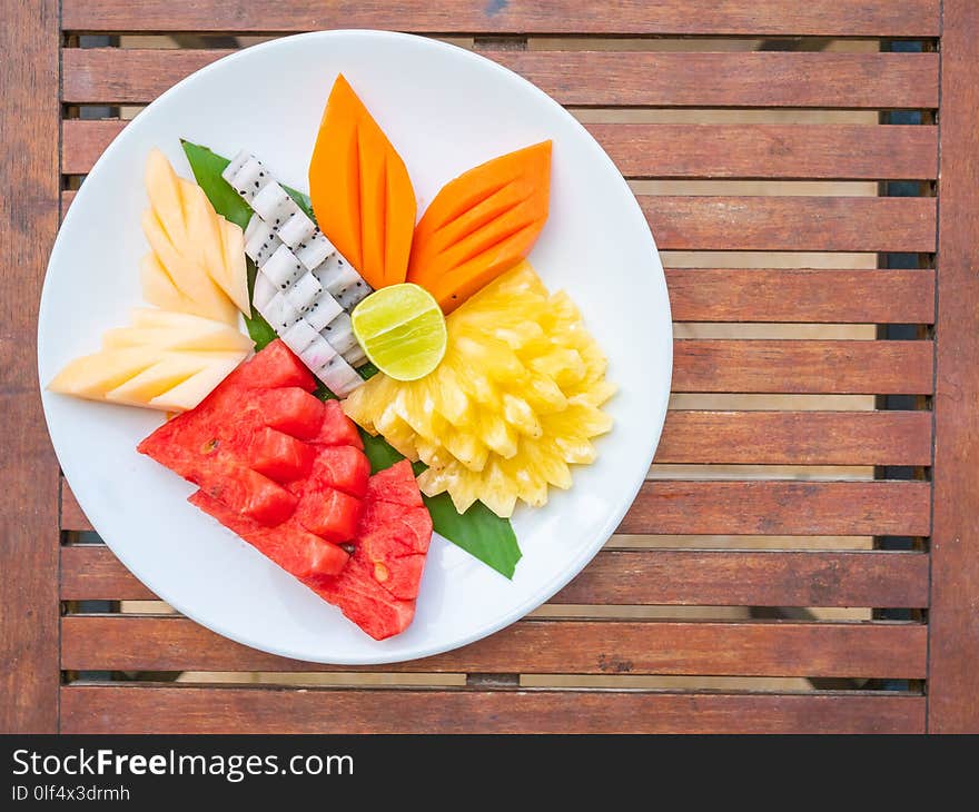 Coloful many fruits in white plate on wooden table - Healthy food style