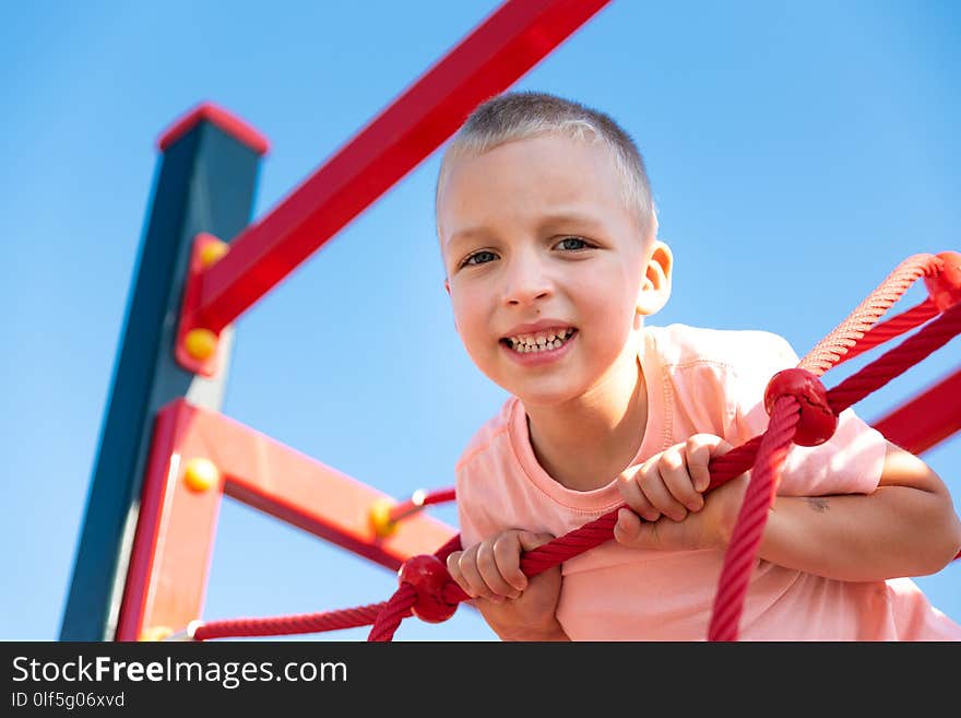 Happy little boy on children playground climbing frame