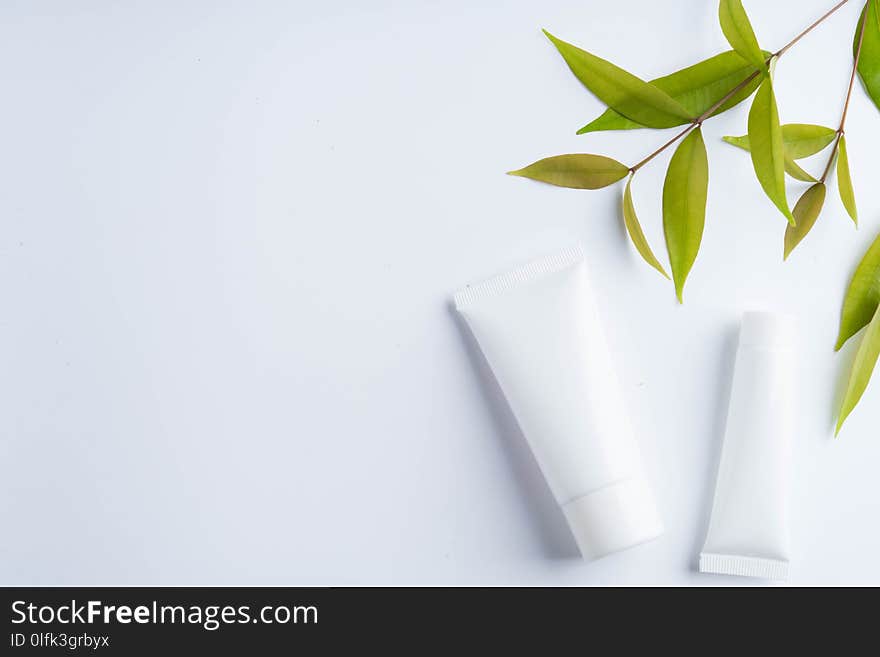 Beautiful natural cosmetics and leaves on light background