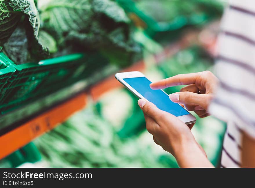 Young woman shopping purchase healthy food in supermarket blur background. Close up view girl buy products using smartphone in sto