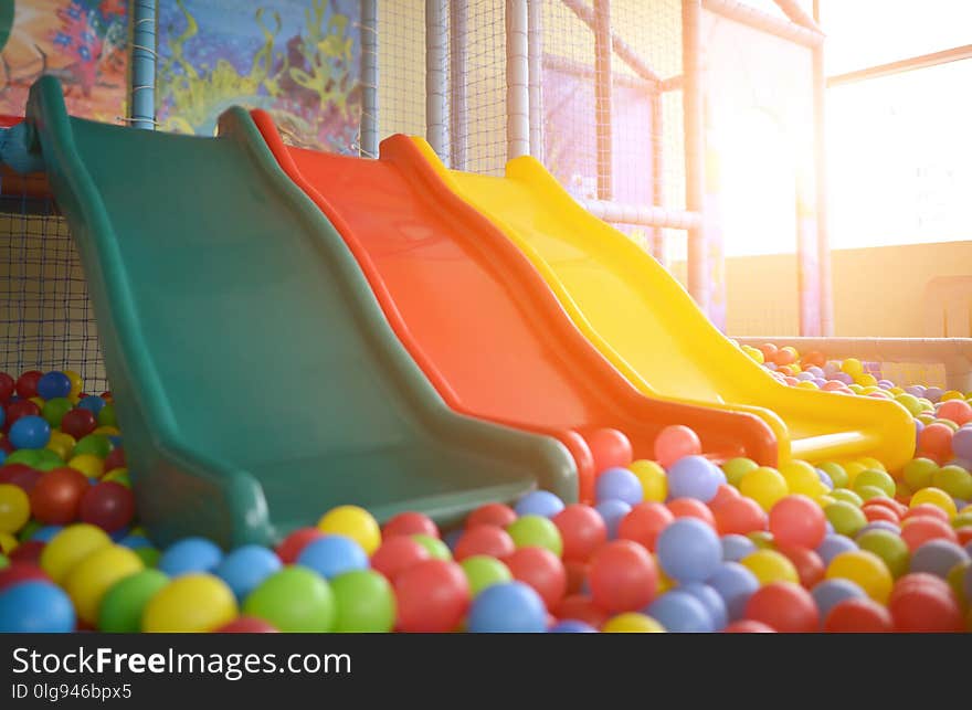 Children playground with plastic slides and colorful balls in pool in rays of the sun